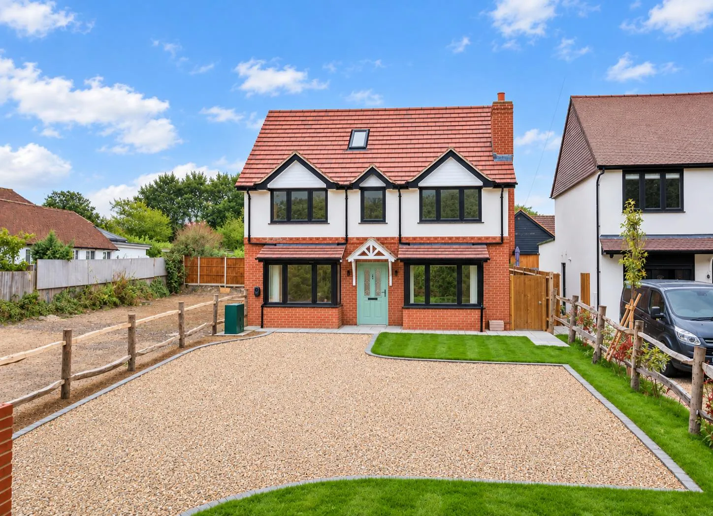 Front elevation of the completed house with gravel driveway and lawn