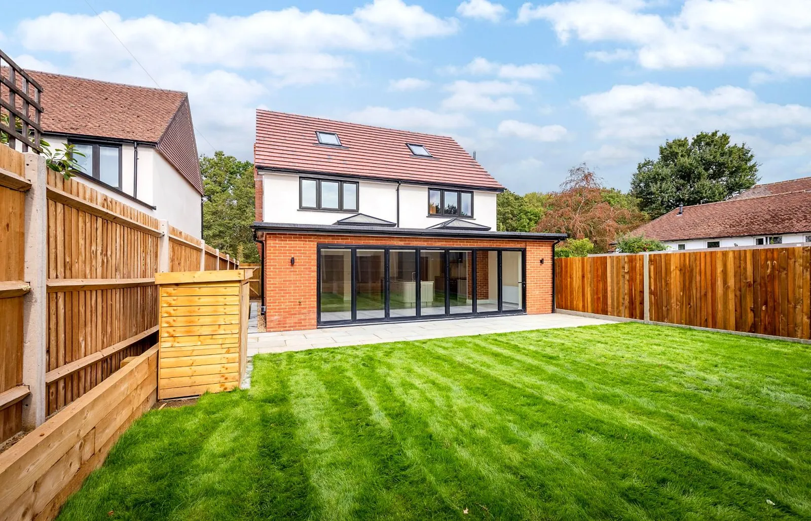 Rear elevation with full-width bi-folding doors onto the patio and lawn